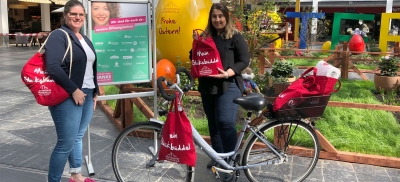 Anne Bahr, Marketingleiterin, und Mercan Songül Aksu mit dem Liefer-Fahrrad, das Sarah Nehls von der Kundeninformation steuert