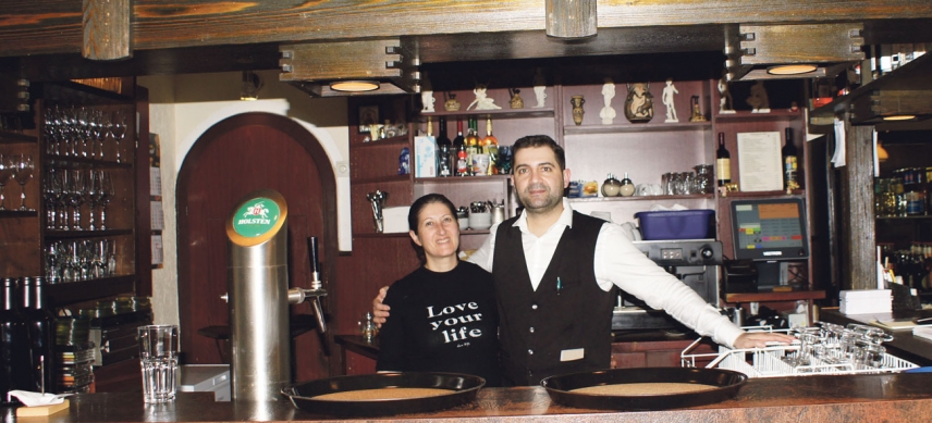 Ioannis Spiros mit seiner Mutter hinter der Bar. Sie hat normaler­weise die Küche fest im Griff... Das Restaurant ist zur Zeit geschlossen – die Abholung von Speisen ist möglich.